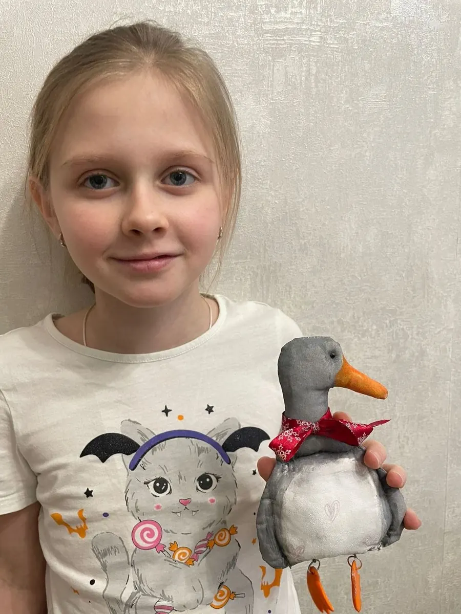 Ученица показывает мягкую игрушку утку ручной работы